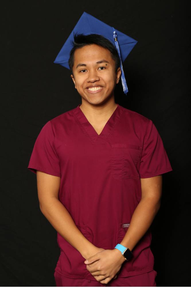 gvsu graduate wearing scrubs and graduation cap